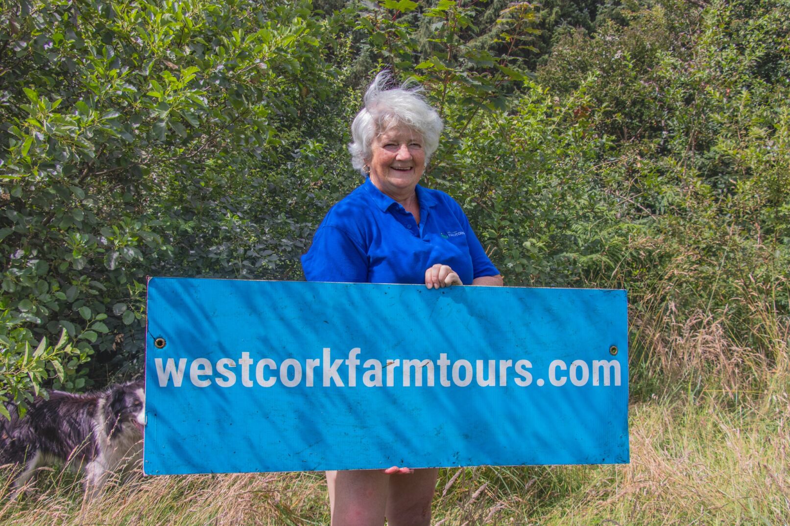Female farmer holding up westcorkfarmtours.com sign
