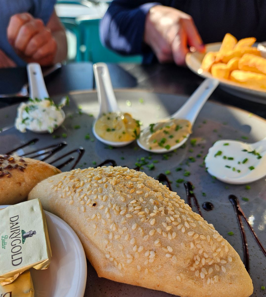 Sesame roll in foreground with taster sauces behind on platter