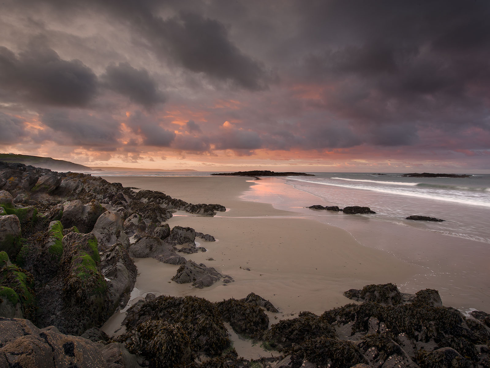 Sunrise seascape showing beach and pink clouds